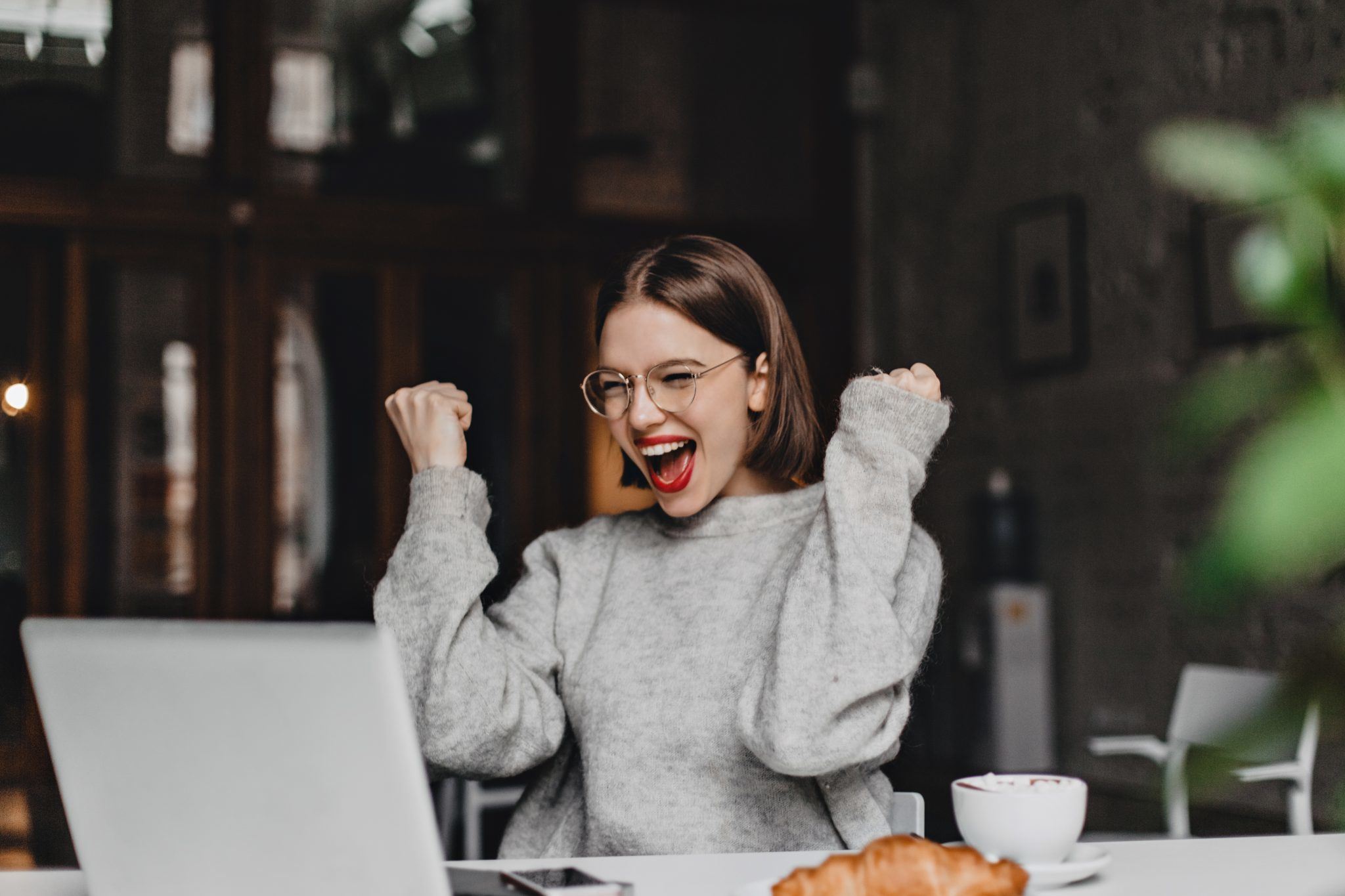 happy woman glasses makes winning gesture sincerely rejoices lady with red lipstick dressed gray sweater looking laptop scaled.jpg?resolution=1536,1